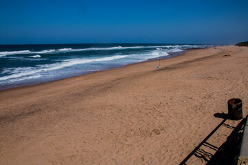 Expansive Beach Sand with Deep Blue Ocean and Clear Sky