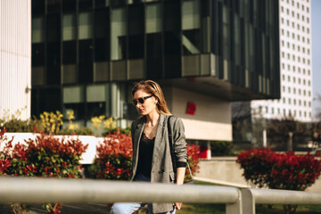 Young Business woman walking into front of office. Wearing black jacket and black sunglasses.