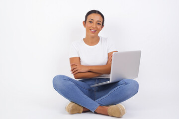 Brunette girl happy face smiling with crossed arms looking confident at the camera standing against gray wall. Positive person.