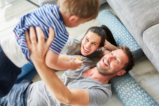 Gl&uuml;ckliche Eltern heben Sohn hoch als Familie zu Hause