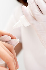 Professional manicurist pouring oil on nails manicure of woman in beauty salon.
