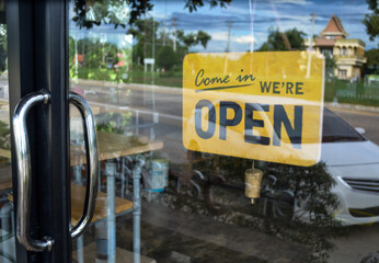 "Come in we're open"sign at cafe front. Yellow wooden label at cafe.