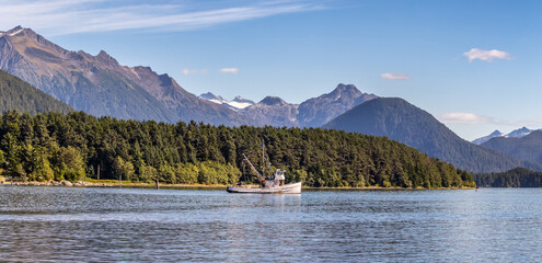 Beautiful panoramic shot of a commercial fishing boat anchored in a harbour in Sitka, AK. Green...