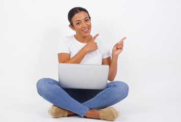 Advertisement concept. Positive, pretty, caucasion woman with beaming smile in jeans shirt on grey background is pointing with her two index finger and looking on empty copy space.