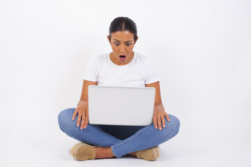 Emotional attractive female with opened mouth expresses great surprisment and frighteness, poses against white concrete background, stares at camera. Unexpected shocking news and human reaction.