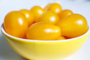 Yellow cherry tomatoes lie in a yellow bowl. Autumn collection of vegetables. Bright harvest