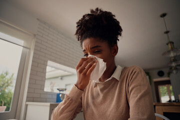 Fototapeta na wymiar Ill sick african american woman blowing running nose got flu caught cold sneezing in tissue - working from home sick