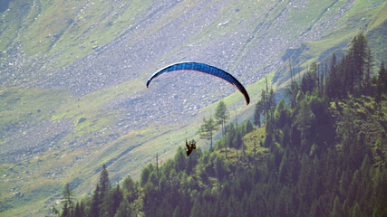 a paraglider in the air in the mountains