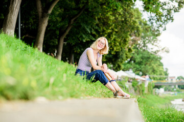 Naklejka na ściany i meble Literature for summer vacation. Girl relaxing at riverside after working day. Rest relax and hobby. Summer vacation. Girl sit on green grass near river and read book. Woman dreaming about vacation