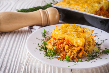 Delicious potato casserole with meat and cheese on a white wooden background