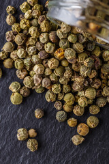 green peppercorns on dark slate stone background