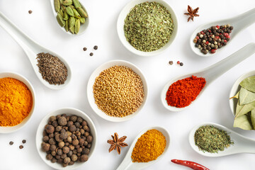 Top view of various spices in bowls and spoons isolated on white background. Flat lay.