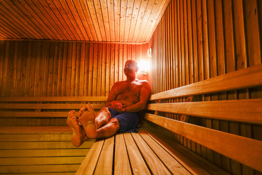 A middle-aged man sits inside of a sauna.