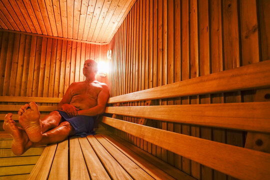 A middle-aged man sits inside of a sauna.