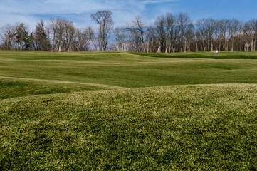Green lawn on a sunny day and two people are walking 

