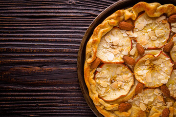 crispy apple galette with almonds on rustic wooden background