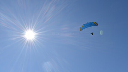 Kitegleiten im Himmel mit Sonne, Gelber und blauer Kite Fallschirm