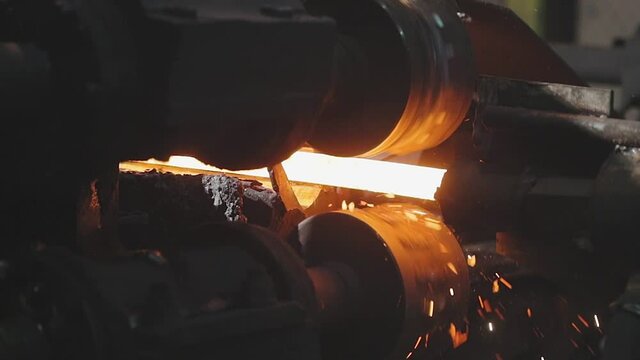 Moving on a hot metal ribbon, production process at a metal rolling plant, rolling metal in production ball production phase, rolling through sparkling metal rollers