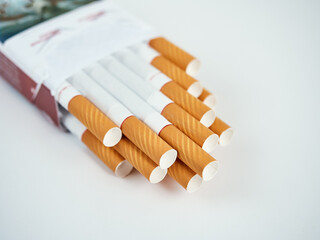 Pack full of filtered cigarettes on a gray background.