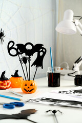 Preparing for Halloween. DIY concept. Halloween decorations on a white desk, indoors. Daytime. Vertical orientation, copy space.
