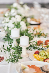 White candles in candlesticks at a wedding celebration. High-quality photo