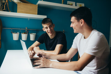 roommates sitting desk using laptop in room