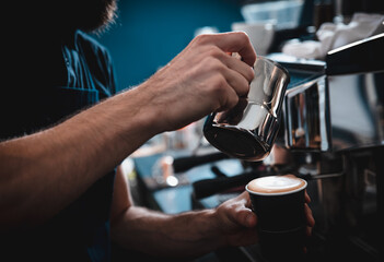 Fototapeta na wymiar Close up of barista hands preparing cappuccino in plastic cup for customer in coffee shop.