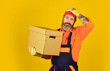 Change is in the air. bearded loader in uniform. Cardboard boxes - moving to a new house. purchase of new habitation or repair of room. Man wearing boilersuit packing boxes. move to new apartment