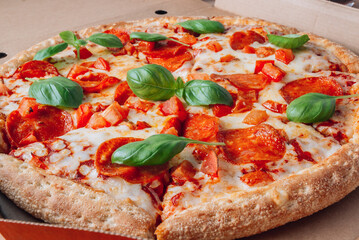 Pizza box delivery concept. Open box with hot tasty italian sliced pepperoni pizza with basil. Selective focus
