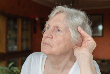 Old woman holding hand at her ear, trying to hear something