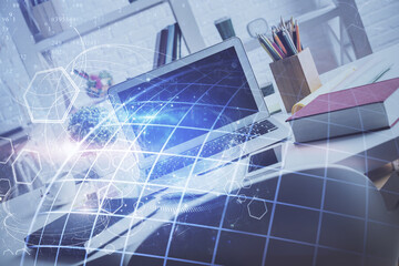Double exposure of desktop with computer and world map hologram. International data network concept.