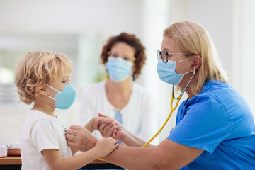 Fototapeta premium Doctor examining sick child in face mask