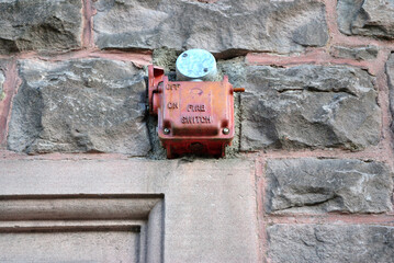 Old Metal Red Emergency Fire Switch above Stone Carved Doorway on Old Stone Wall