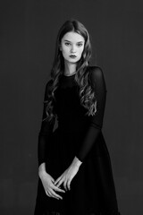 Fototapeta premium Portrait of a young woman in a black dress on a dark background