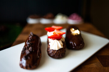 Eclairs of different flavors set on a dark background for a restaurant menu