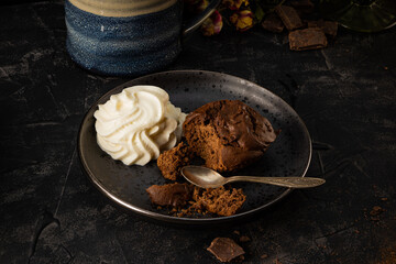 Homemade chocolate brownie with whipped cream on a plate. Dark photo