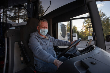 Bus driver wearing a medical mask, looking out of the bus window
Safe driving during a pandemic, protection against coronavirus