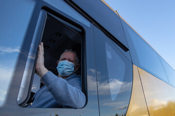 Bus driver wearing a medical mask, looking out of the bus window
Safe driving during a pandemic, protection against coronavirus