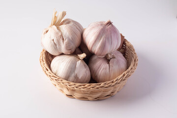 A wicker basket with garlic on a white background