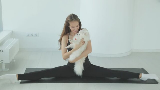 A sporty girl trains in the gym with a dog. Portrait of a girl with a small dog, smiling and laughing.