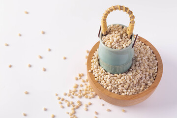 Barley rice in wooden cup and ceramic basket on white background