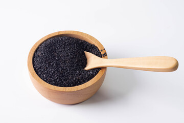 Black sesame seeds in a wooden cup on a white background