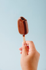 Chocolate cake in the form of ice cream on a stick on a white plate and a colored background