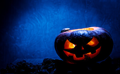 pumpkin in the shape of a skull for halloween in a witch hat on a dark background, smoke comes from...