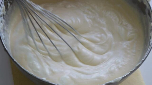 Woman mixing cottage of tasty cheesecake and preparing of basque burnt cheesecake in the metal pot. Making tasty basque burnt cheesecake. Preparing of San Sebastian cheesecake step by step process on 