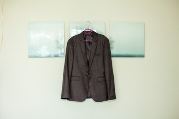 a man's jacket hangs on a white wall