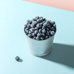 Frozen blueberries in a metal pot against a blue background.