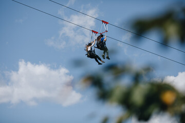 a brave man descends on a zip line high in the mountains above the forest