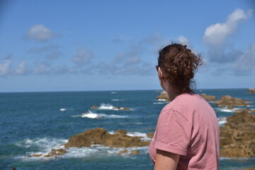 Blick einer Frau von hinten Richtung Horizont an der Küste der Bretagne. 