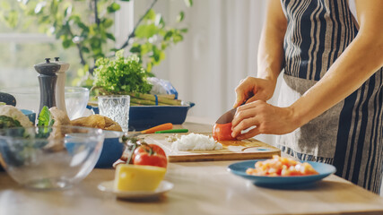 Close Up Shot of a Man Chopping a Tomato with a Sharp Kitchen Knife. Preparing a Healthy Organic Salad Meal in a Modern Kitchen. Natural Clean Diet and Healthy Way of Life Concept.